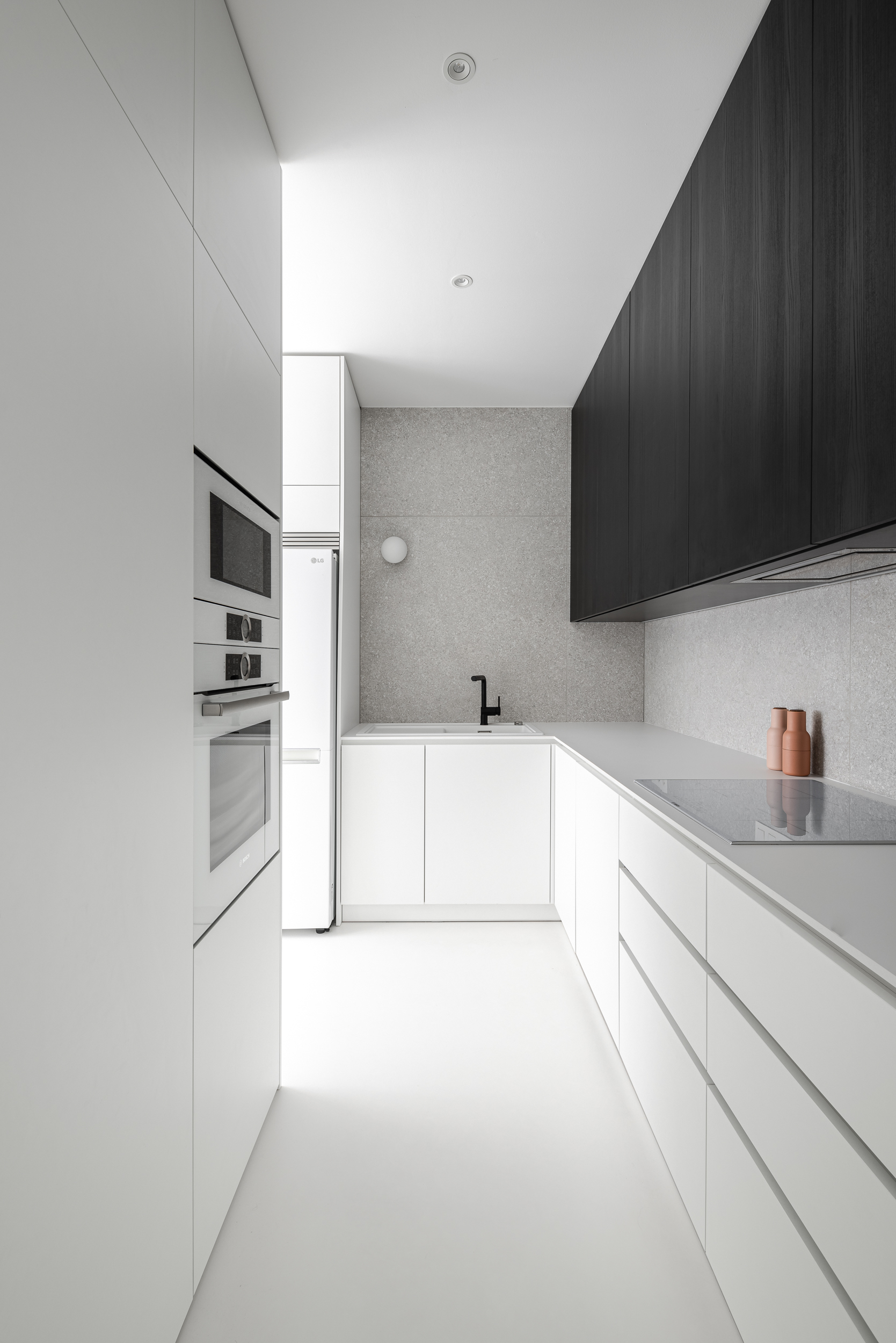 Kontinuita: biela kuchynský linka i ďalší nábytok v priestore bytu „STJR“ je organickým pokračovaním liatej bielej podlahy.
