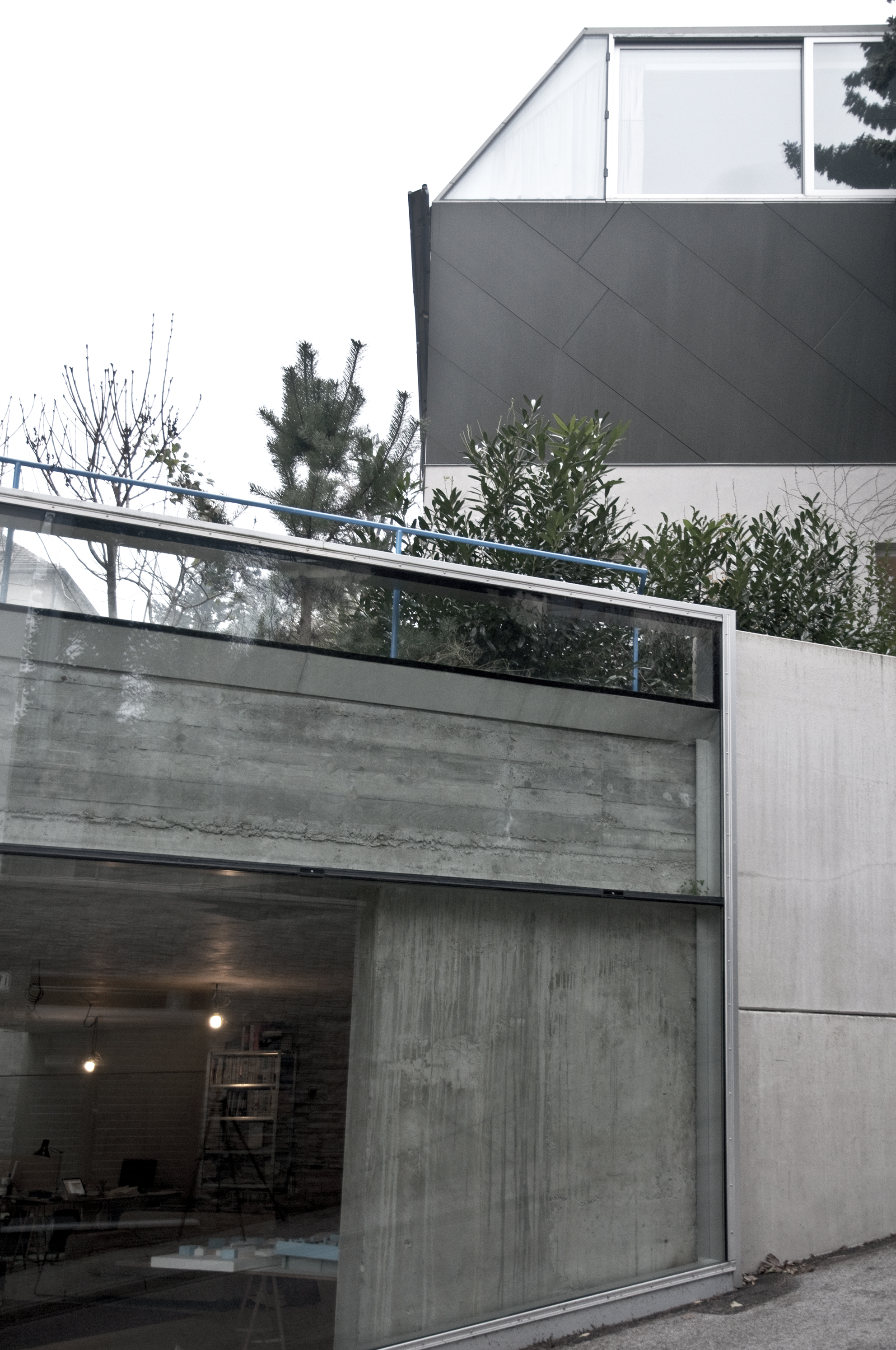 Na spodnej strane domu, v bezprostrednpm kontakte s ulicou je umiestnený ateliér architekta. Charakteristická je transparentnosť, priznanie vnútorného obsahu a materiálového riešenia (surový pohľadový betón).