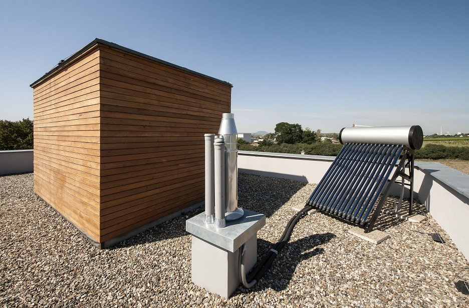 Drevené schodisko prechádza stredom domu až do strešnej nadstavby s terasou, ktorá ponúka ďalší, odlišný obytný priestor